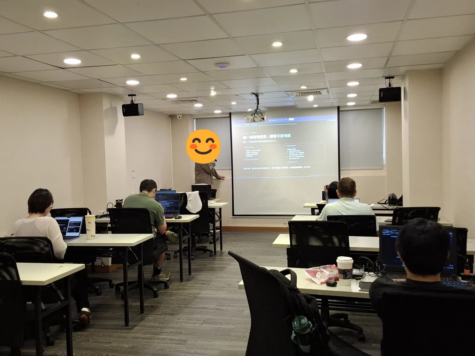 Claude 實戰訓練營第 2 週實體課現場，學員各自用筆電跟著操作，投影幕正在講角色設定